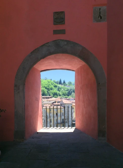 Steinbogen mit Blick auf eine sonnige Landschaft mit Häusern und Bäumen